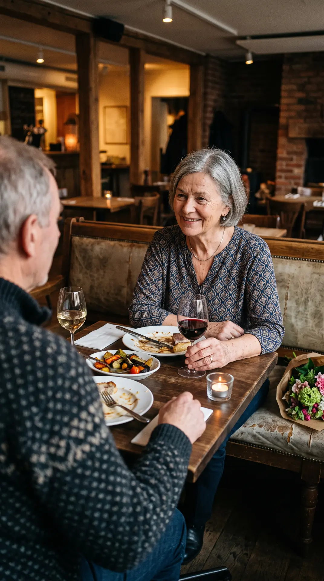 Et eldre par deler en middag ved et restaurantbord med levende lys